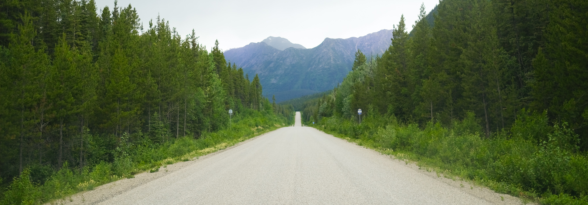 An open, rustic highway going towards some mountains.